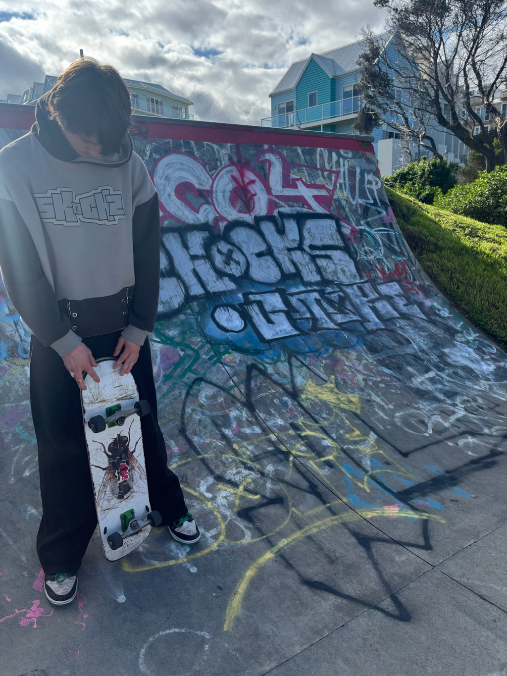 SKOCKZ Signature Hoodie worn at a Warrnambool skate park - cream and brown colour-block hoodie with outlined SKOCKZ chest logo and zip-detail hem