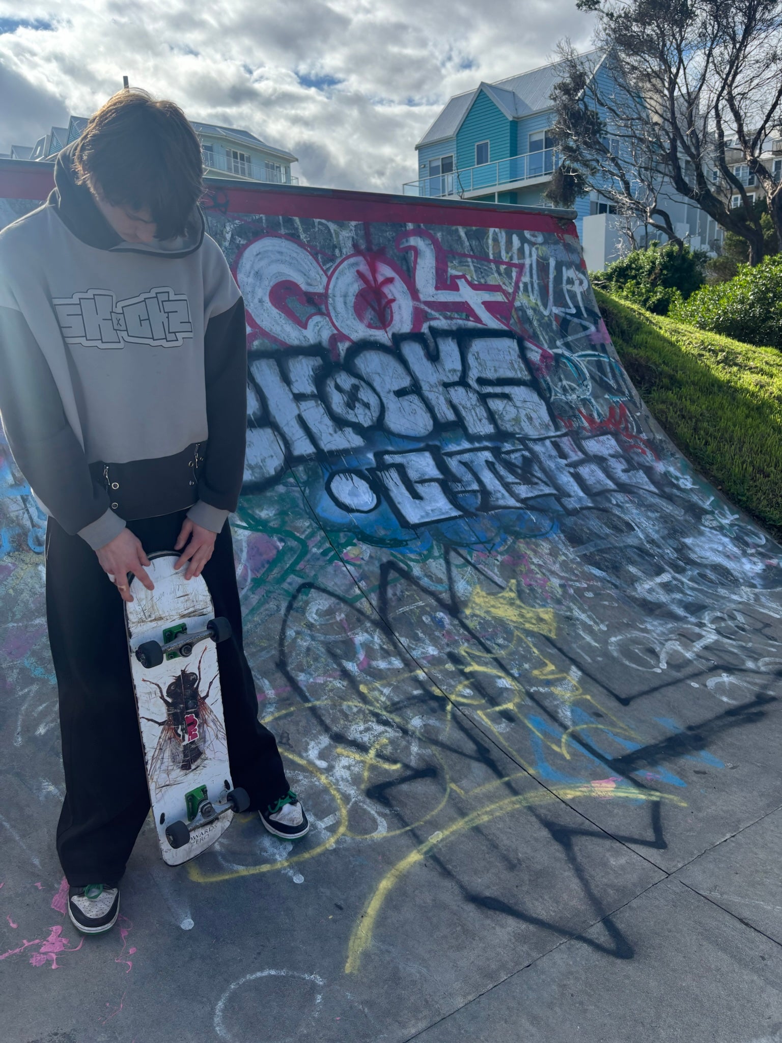 SKOCKZ Signature Hoodie worn at a Warrnambool skate park - cream and brown colour-block hoodie with outlined SKOCKZ chest logo and zip-detail hem